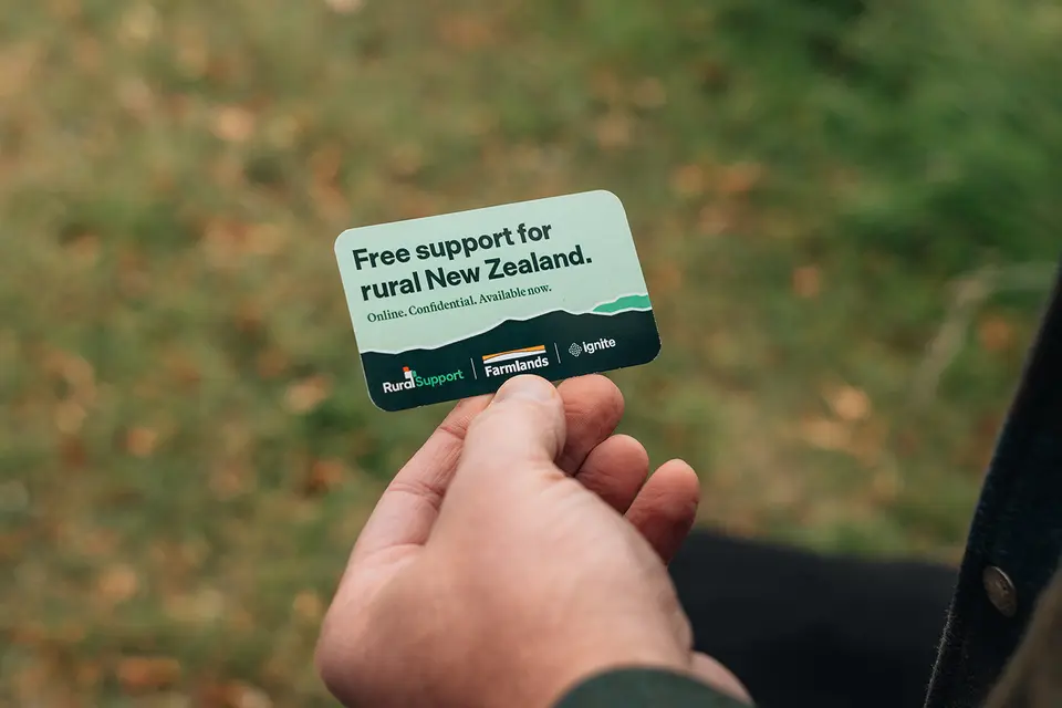 A hand holds a card reading "Free support for rural New Zealand." Logos for Rural Support Trust, Farmlands, and Ignite are visible.