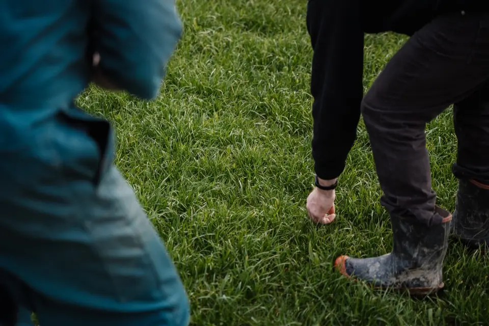 Specialist Services: Two people on grass; one in a blue jacket, the other in black, bends down wearing muddy boots.