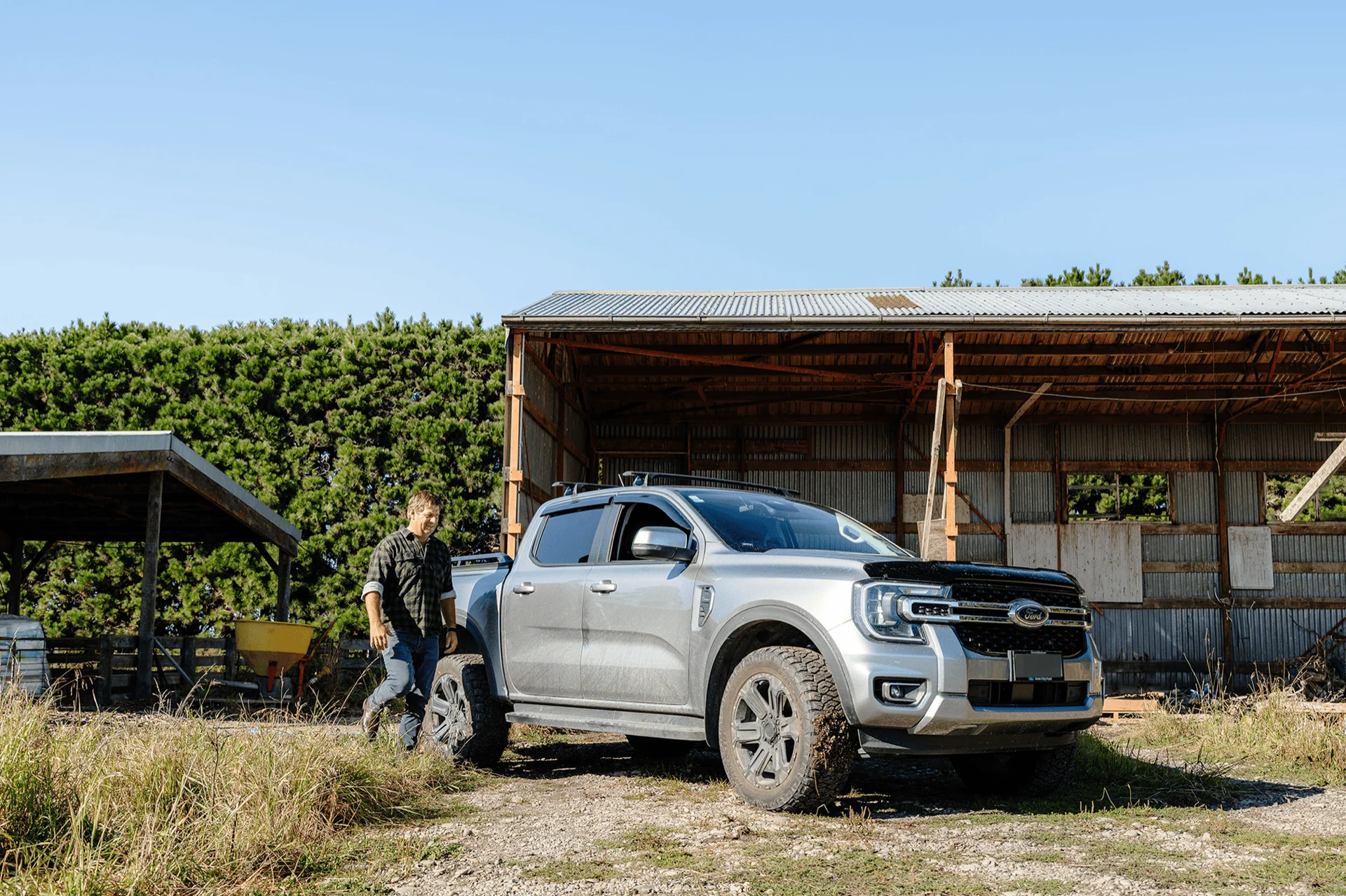 Farmer beside a pickup truck at a rural barn