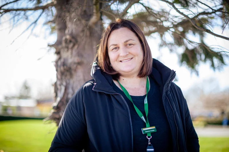 Smiling woman with a Farmlands lanyard outdoors