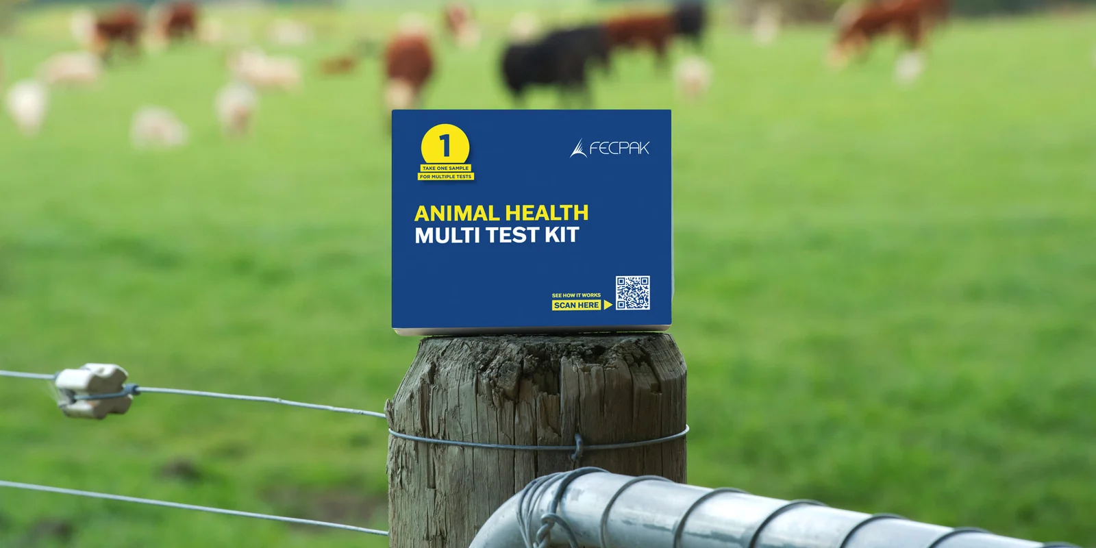 Animal health multi test kit box on a fence post with a blurred background of grazing animals in a green field.