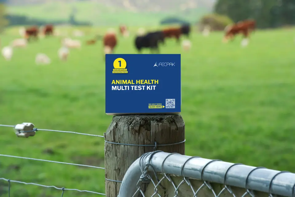 Animal health multi test kit box on a fence post with a blurred background of grazing animals in a green field.