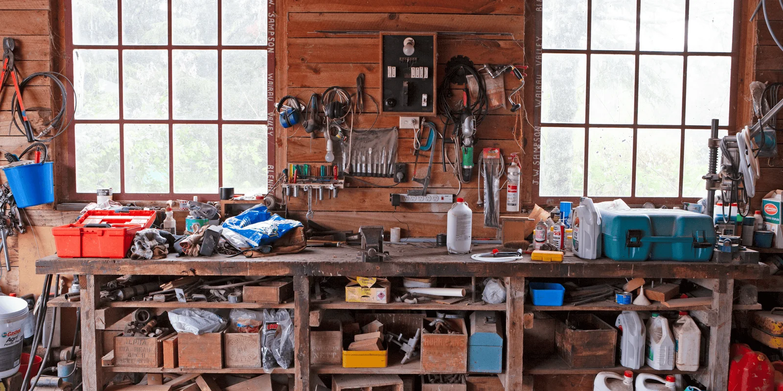 Preventing rural crime in NZ: A cluttered workshop with tools hanging on a wooden wall, a workbench filled with supplies